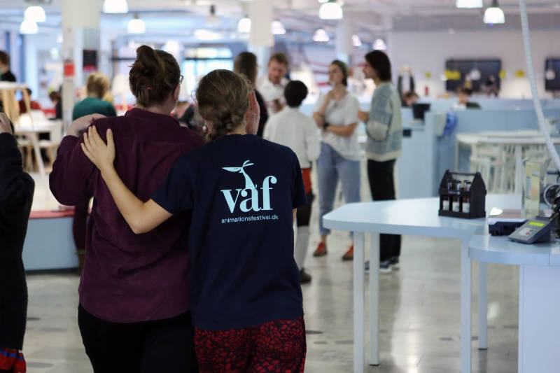 The volunteer stands with her back turned, wearing a blouse with the VAF logo visible.